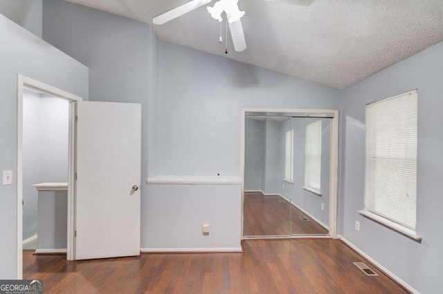 unfurnished bedroom with ceiling fan, a textured ceiling, dark wood-type flooring, a closet, and vaulted ceiling