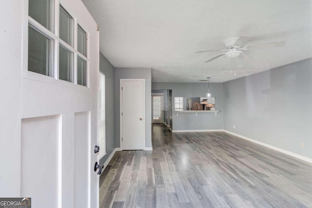 unfurnished living room with ceiling fan, wood-type flooring, and a textured ceiling