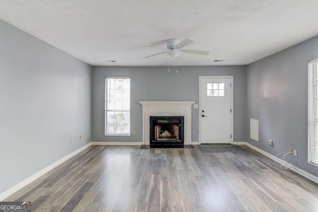 unfurnished living room with hardwood / wood-style flooring, a textured ceiling, a healthy amount of sunlight, and ceiling fan