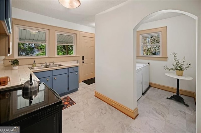 kitchen with sink, washer and dryer, and blue cabinets