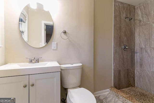 bathroom featuring toilet, vanity, and a tile shower