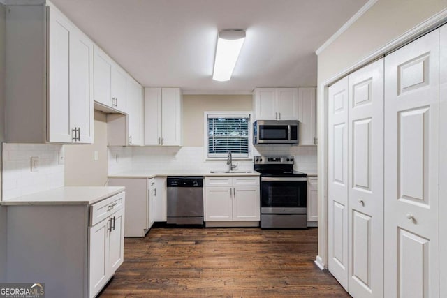 kitchen featuring white cabinetry, appliances with stainless steel finishes, backsplash, dark hardwood / wood-style floors, and sink