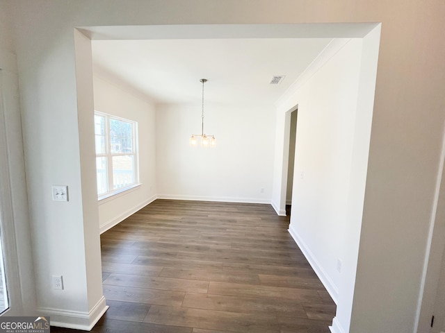 unfurnished dining area featuring a notable chandelier, ornamental molding, and dark hardwood / wood-style floors