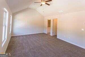 carpeted empty room featuring ceiling fan and lofted ceiling