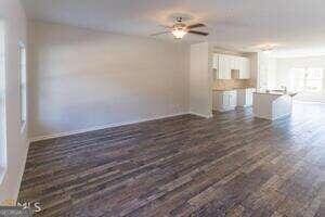 unfurnished living room with ceiling fan and dark wood-type flooring