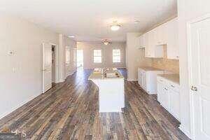 kitchen with white cabinetry, an island with sink, and dark wood-type flooring