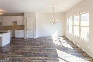 unfurnished dining area with a chandelier and dark wood-type flooring