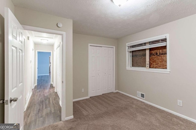 unfurnished bedroom with a closet, a textured ceiling, and light carpet