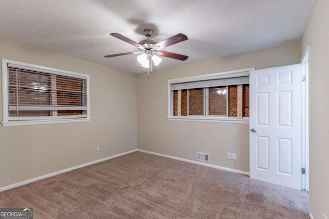 carpeted empty room featuring a textured ceiling and ceiling fan