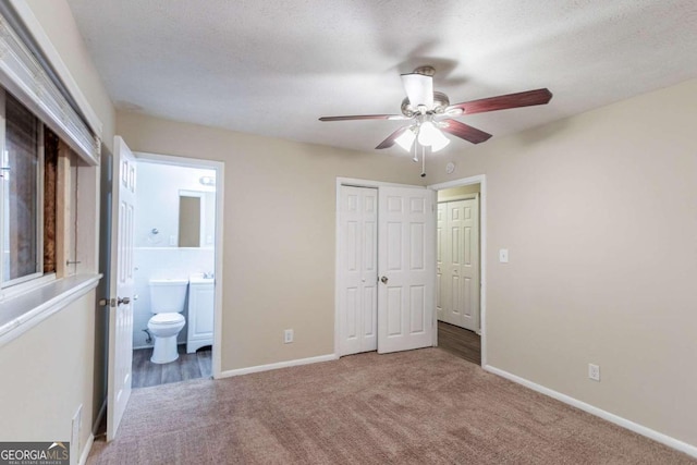 unfurnished bedroom with carpet flooring, a textured ceiling, ensuite bathroom, ceiling fan, and a closet