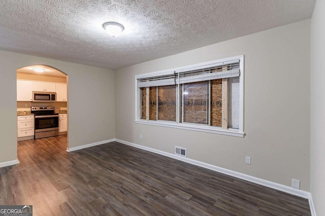 empty room featuring dark wood-type flooring and a textured ceiling