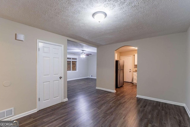 empty room featuring dark hardwood / wood-style flooring, a textured ceiling, and ceiling fan