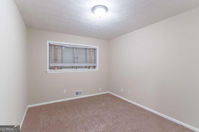 empty room featuring a textured ceiling and carpet floors