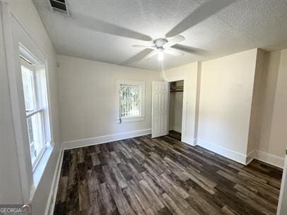 unfurnished bedroom with dark wood-type flooring, ceiling fan, a textured ceiling, and a closet