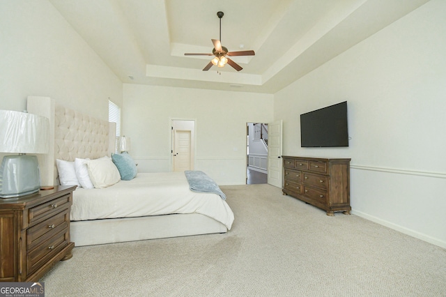 carpeted bedroom with a tray ceiling and ceiling fan