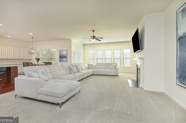 carpeted living room with ceiling fan with notable chandelier