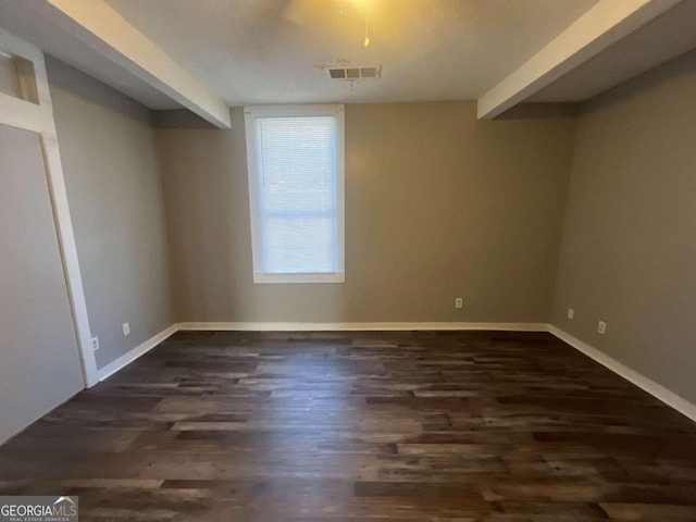 empty room featuring dark hardwood / wood-style flooring and beamed ceiling