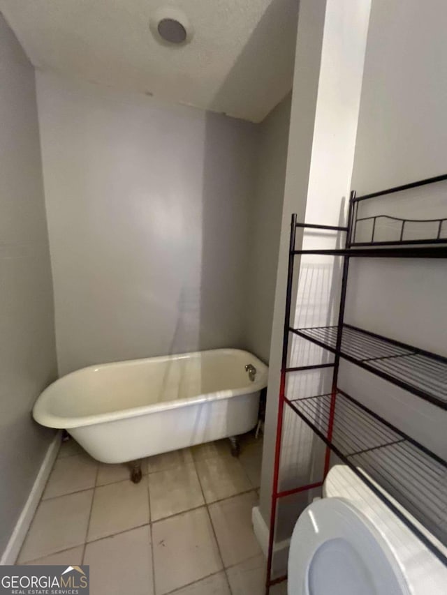 bathroom with tile patterned floors, a tub to relax in, and toilet