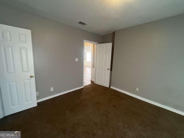 unfurnished bedroom featuring dark colored carpet