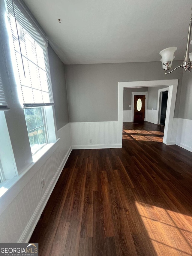 empty room featuring a chandelier and dark hardwood / wood-style flooring