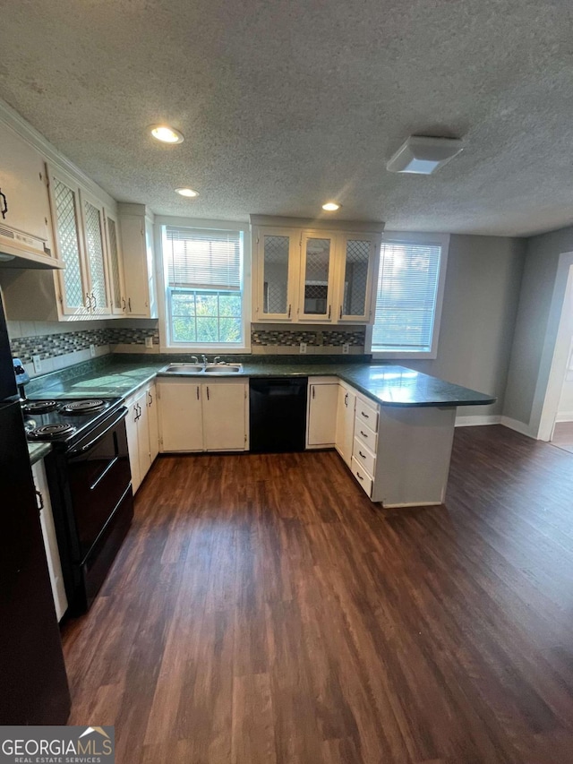 kitchen with dark wood-type flooring, a healthy amount of sunlight, black appliances, and kitchen peninsula