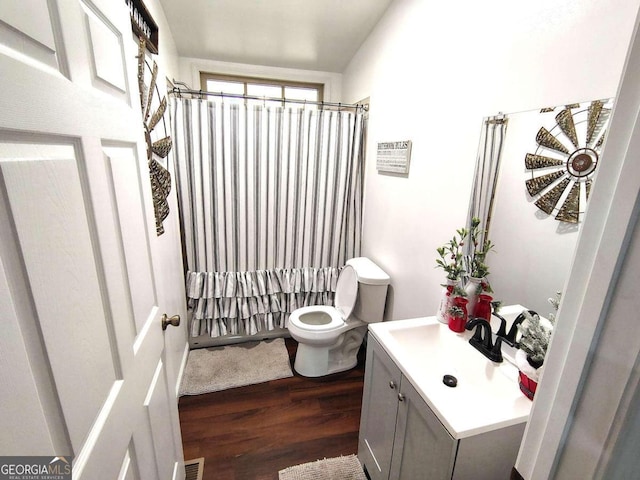 bathroom with a shower with shower curtain, hardwood / wood-style flooring, vanity, and toilet