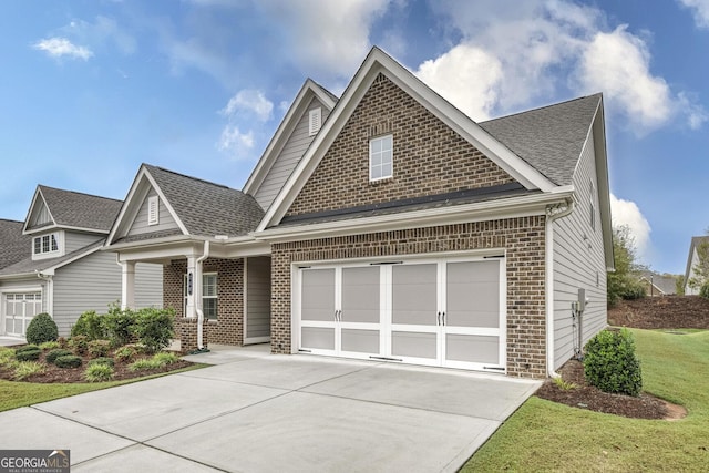 craftsman-style house with concrete driveway, a garage, a shingled roof, and brick siding