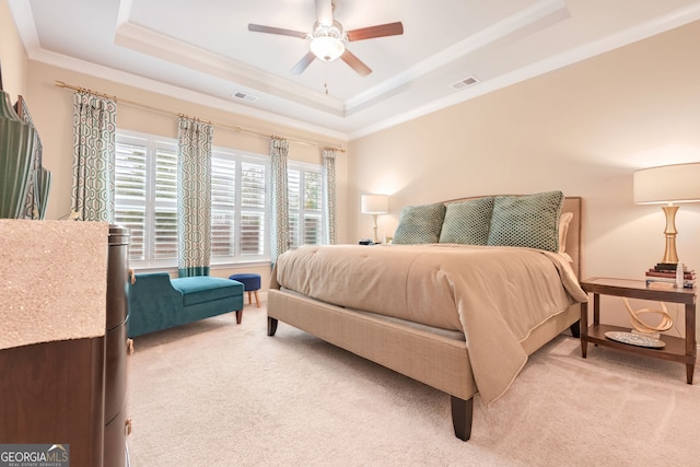 bedroom with light colored carpet, visible vents, and a tray ceiling