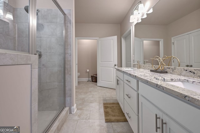 bathroom with a sink, double vanity, a stall shower, toilet, and tile patterned floors