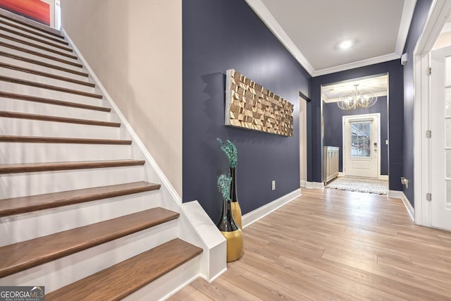 entrance foyer featuring wood finished floors, an inviting chandelier, baseboards, stairway, and crown molding