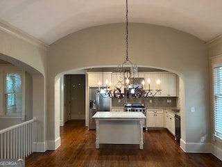 kitchen with dark hardwood / wood-style flooring, a center island, decorative light fixtures, and vaulted ceiling