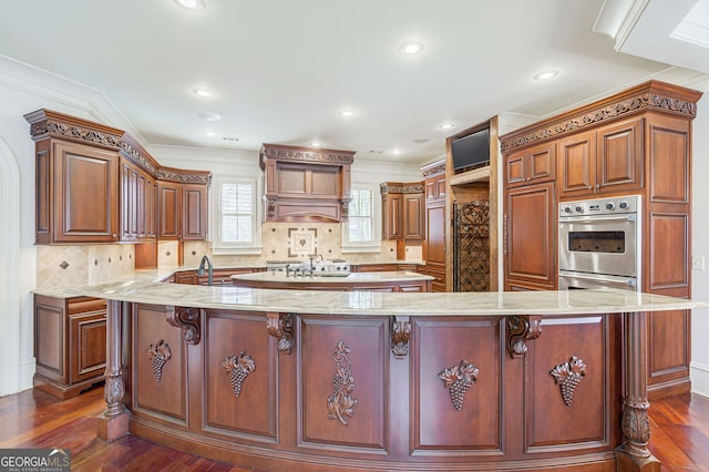 kitchen featuring ornamental molding, a kitchen bar, dark hardwood / wood-style flooring, and stainless steel oven