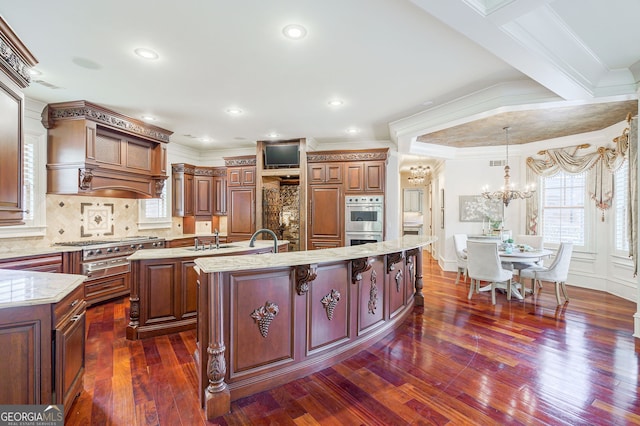 kitchen featuring a center island with sink, crown molding, appliances with stainless steel finishes, dark hardwood / wood-style floors, and sink