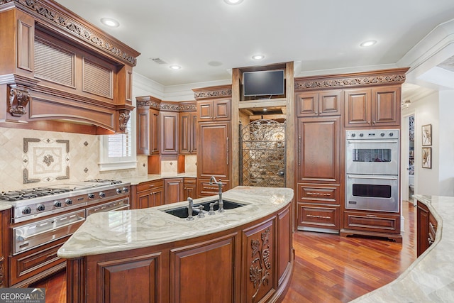 kitchen featuring dark hardwood / wood-style flooring, sink, a kitchen island with sink, crown molding, and appliances with stainless steel finishes