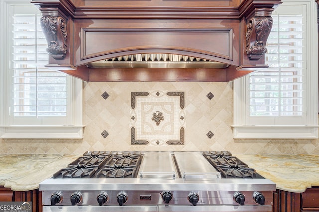 kitchen with light stone countertops, backsplash, and stainless steel range oven