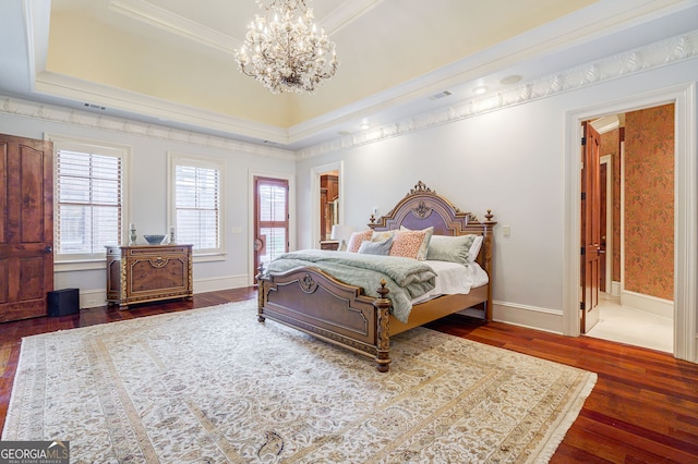 bedroom featuring ensuite bath, dark hardwood / wood-style floors, an inviting chandelier, a tray ceiling, and crown molding