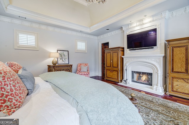 bedroom featuring wood-type flooring, ornamental molding, and a tray ceiling