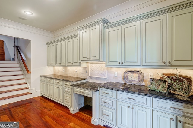 kitchen featuring ornamental molding, dark hardwood / wood-style flooring, dark stone counters, and backsplash