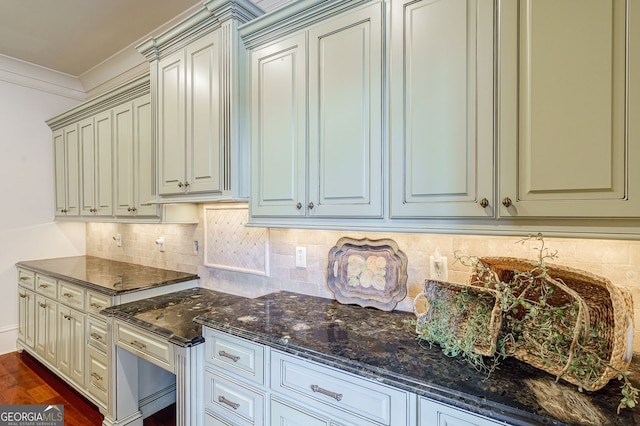 kitchen with dark wood-type flooring, dark stone counters, backsplash, and crown molding