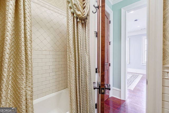 bathroom featuring hardwood / wood-style flooring, shower / bath combo with shower curtain, and crown molding