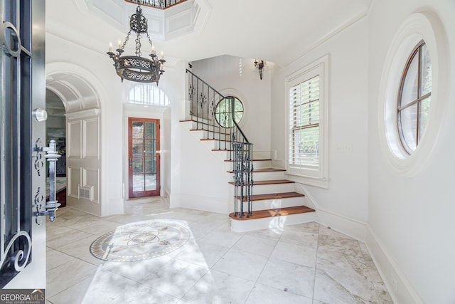 entryway featuring crown molding and an inviting chandelier