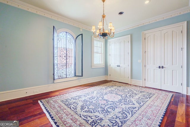 foyer with a chandelier, wood-type flooring, and ornamental molding