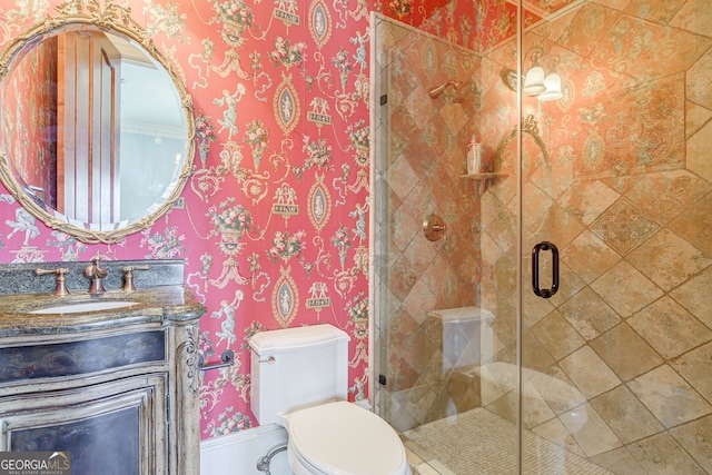 bathroom featuring toilet, vanity, and a shower with door