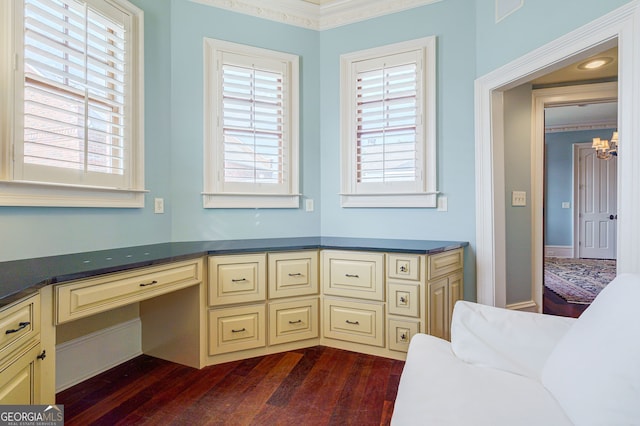 unfurnished office featuring built in desk, dark hardwood / wood-style flooring, and ornamental molding