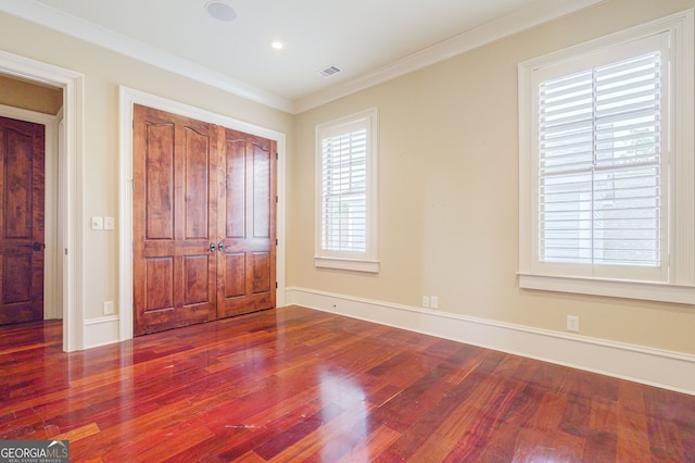 unfurnished bedroom featuring multiple windows, hardwood / wood-style floors, and crown molding