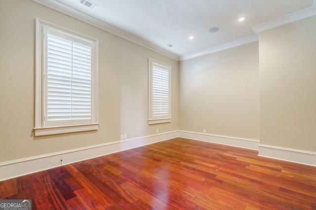 spare room with ornamental molding, plenty of natural light, and wood-type flooring