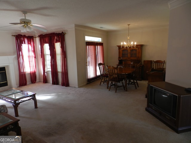 dining area with a tiled fireplace, carpet, crown molding, and ceiling fan with notable chandelier