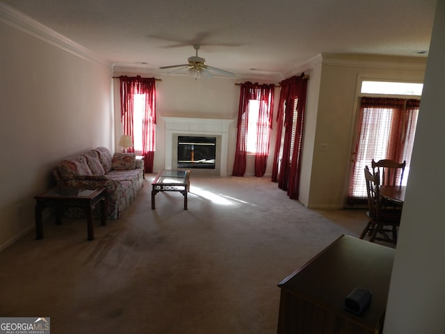 carpeted living room with ceiling fan, a healthy amount of sunlight, and crown molding