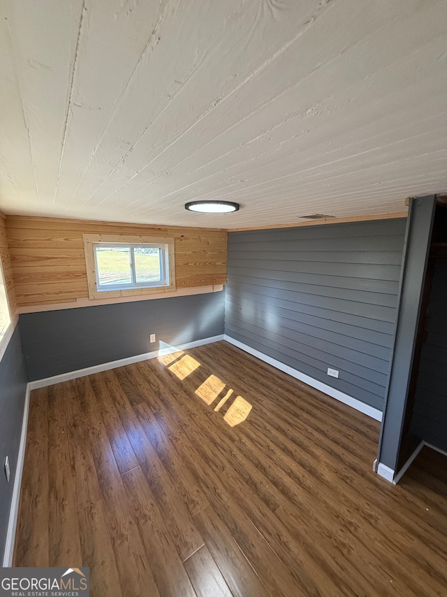 bonus room featuring wooden walls and dark hardwood / wood-style flooring