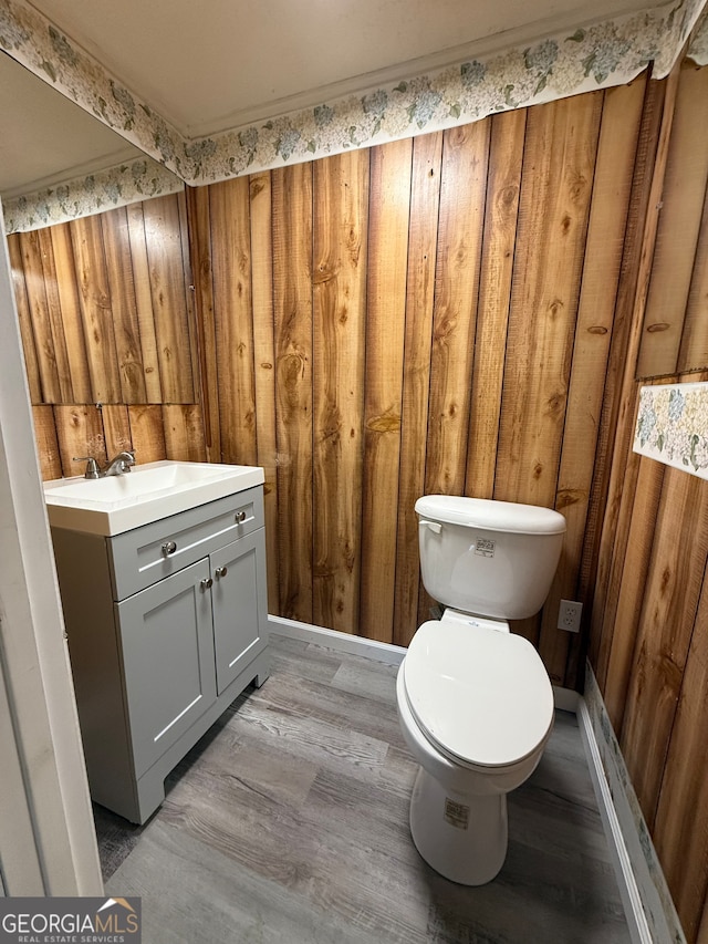 bathroom featuring vanity, hardwood / wood-style flooring, toilet, and wooden walls